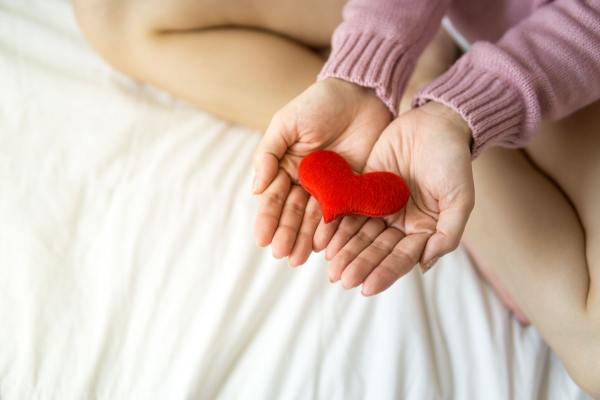 Person holding a heart shape in their hands representing self-compassion