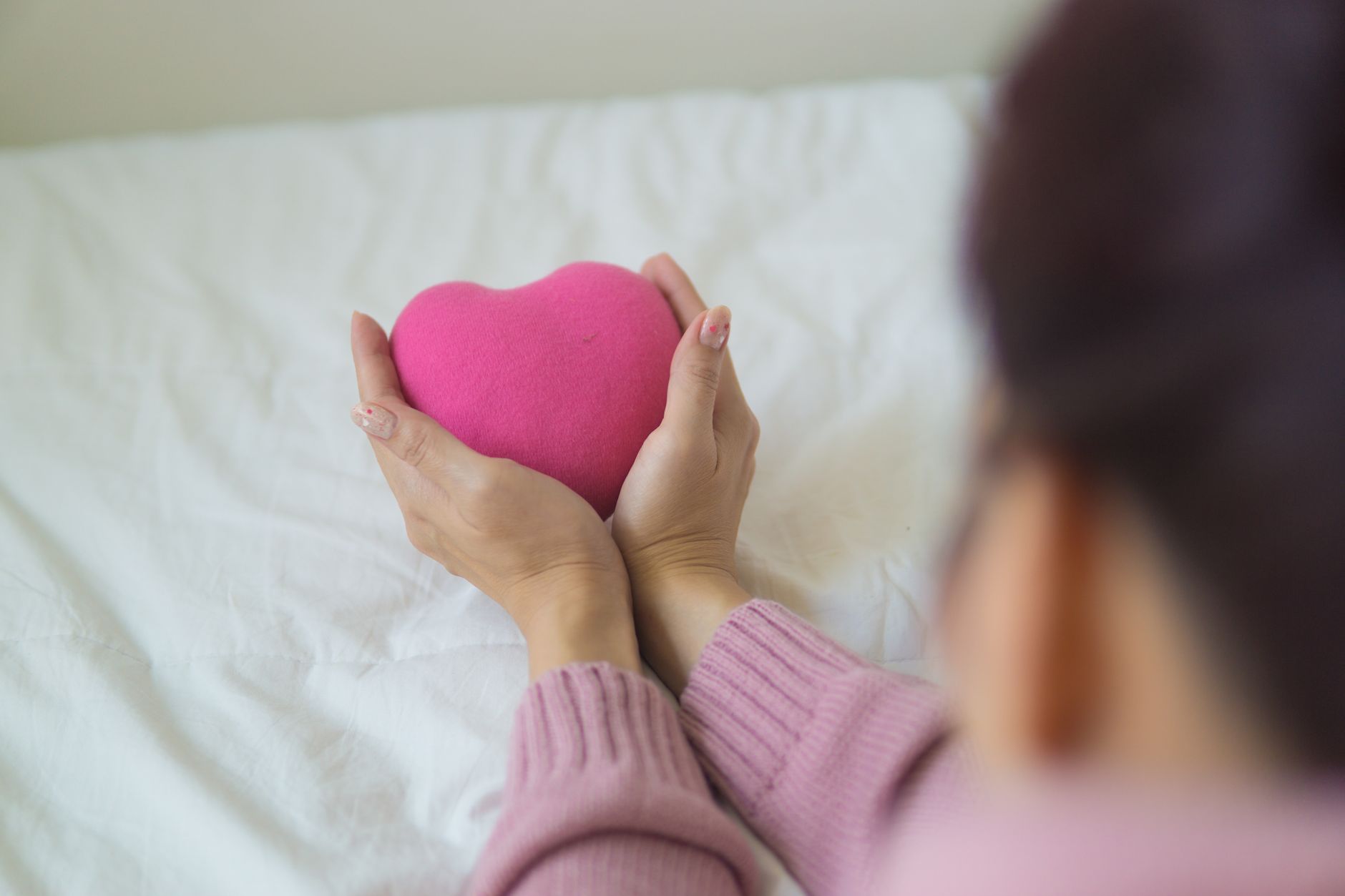 long covid heart palpitations natural support — From above of unrecognizable female in sweater sitting on white blanket with pink heart shaped exercise ball in light room
