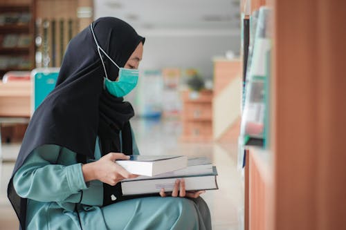 Woman Wearing Face Mask Holding a Book