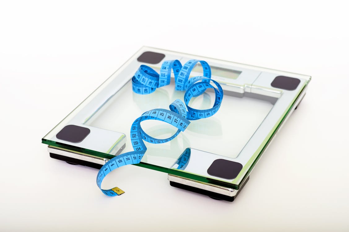 透明なガラスの正方形の体重計で測定する青いテープ