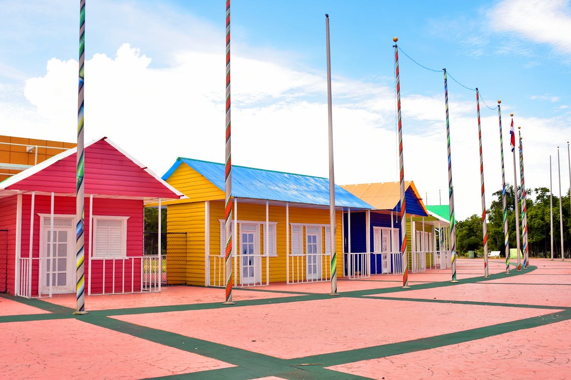 Free Brightly painted houses with flag poles under clear skies. Ideal for architecture and travel themes. Stock Photo