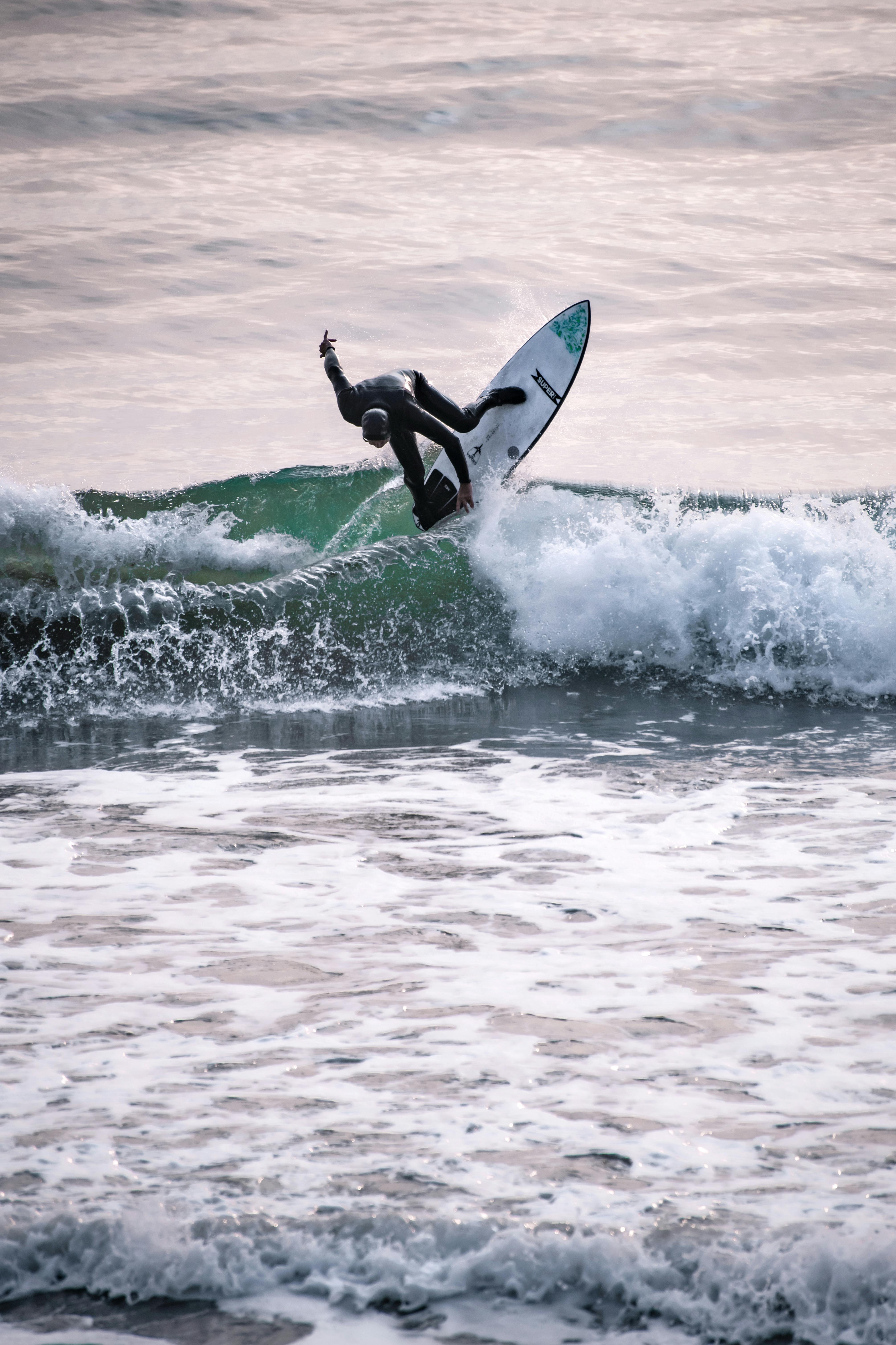 A surfer performs an impressive maneuver on ocean waves in Cambria, CA. Perfect example of extreme sports action photography.