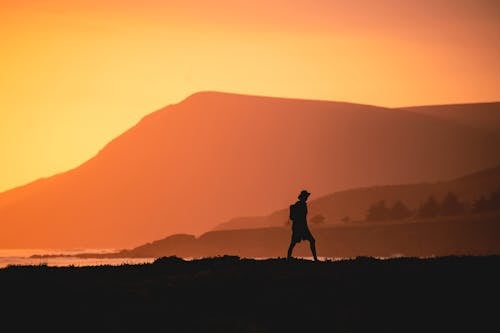 Free Silhouette person Standing on the Seaside During Sunset Stock Photo