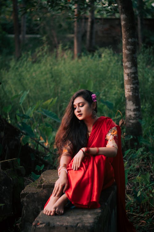 Allure Indian woman in traditional suit chilling on stone slab in park in summertime