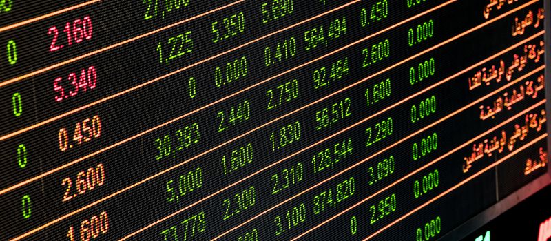 株式市場のモニターに株価や指標が表示され、金融取引の活況を示すイメージ