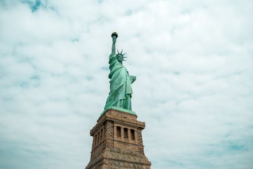 Free Iconic Statue of Liberty against a cloudy sky in New York City, symbolizing freedom. Stock Photo