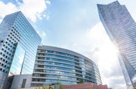 现代摩天大楼将阳光反射到城市景观的蓝天上