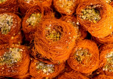 Close view of golden shredded pastry nests filled with chopped pistachios