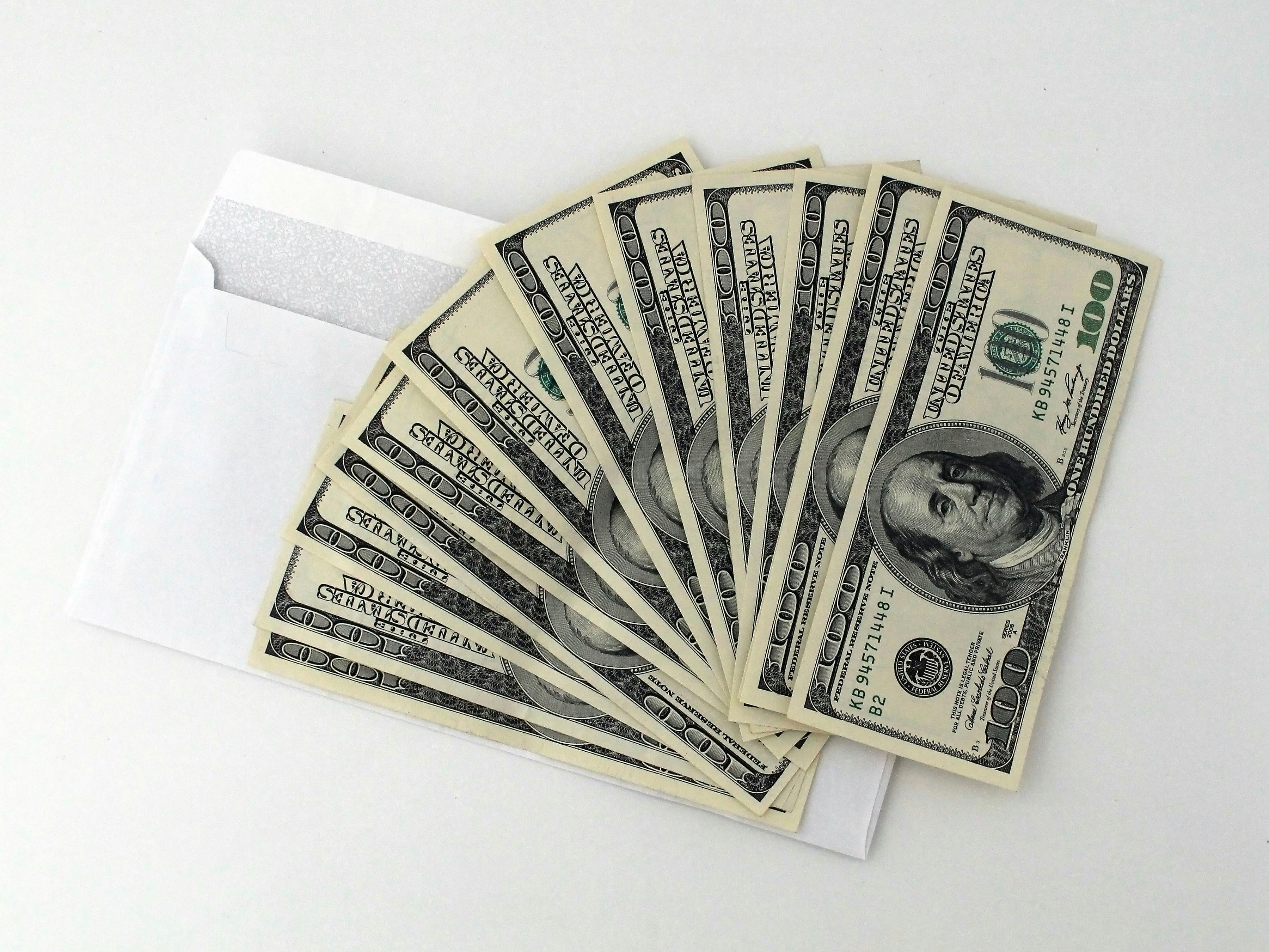 An envelope with several one hundred dollar bills fanned out, symbolizing available cash and working capital loans for business growth