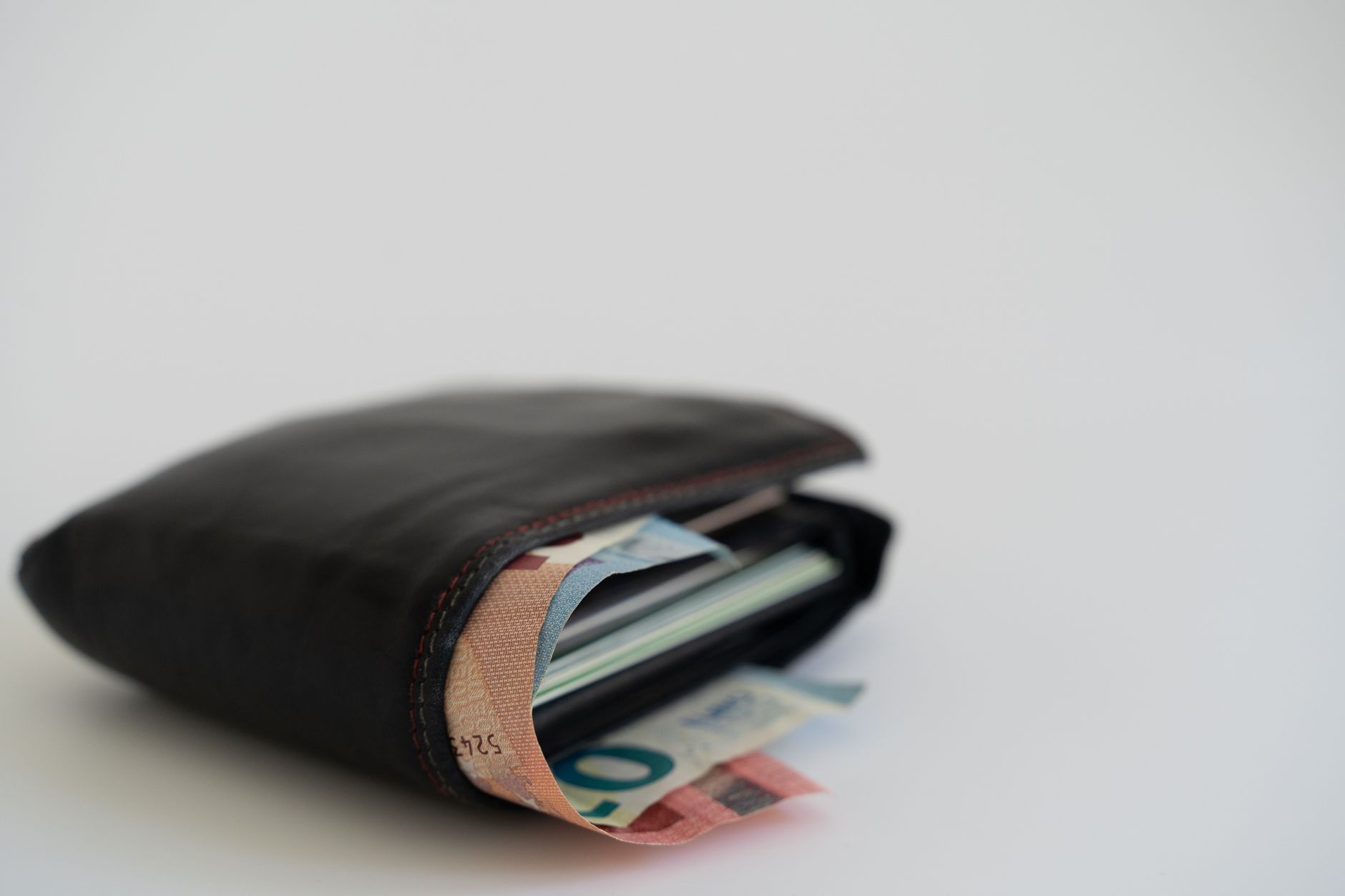 Close-up of a leather wallet filled with Euro banknotes on a white background, perfect for financial and lifestyle theme
