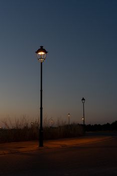 Capture of illuminated lampposts along a quiet street at twilight in La Roda, Spain.