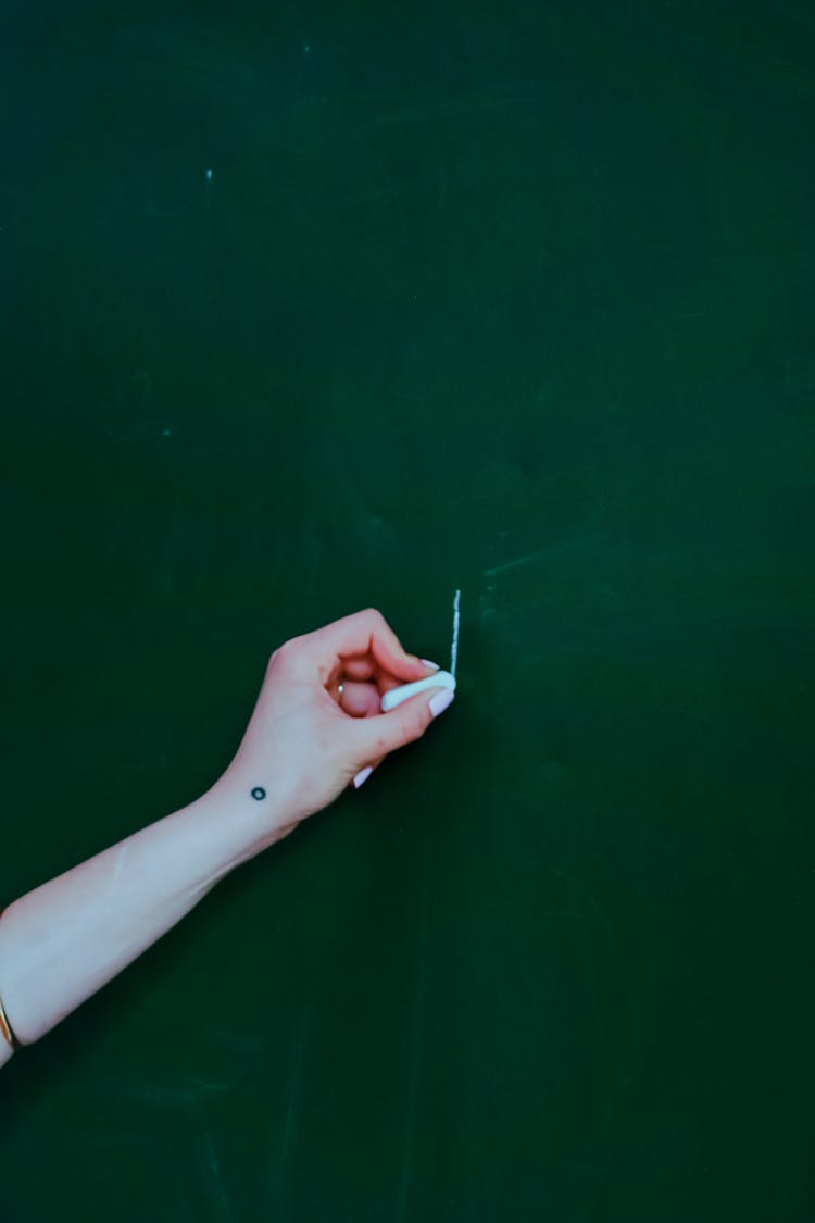 Crop Woman Writing On Green Chalkboard