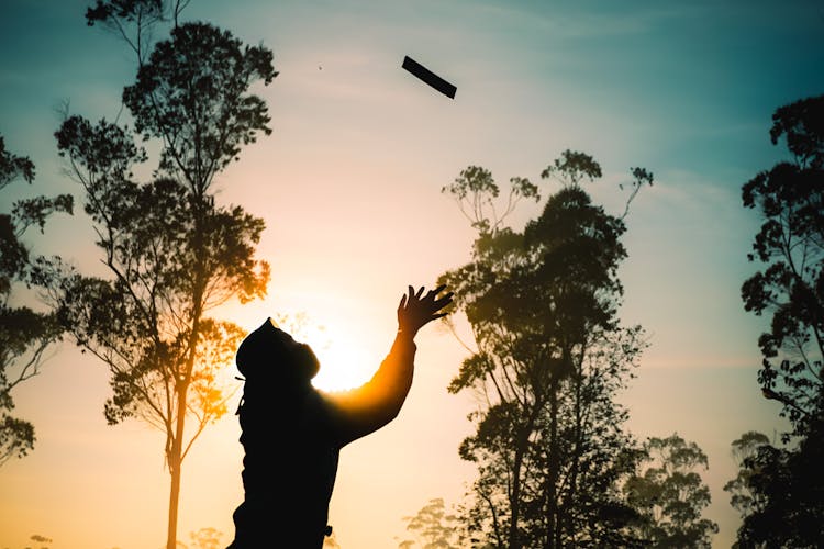 Silhouette Of Man Throwing Object In Air