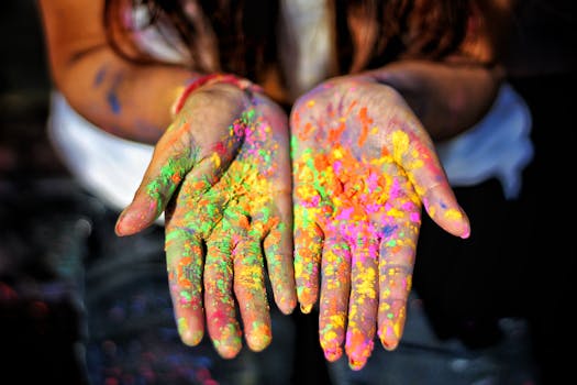 Close-up of colorful powdered hands during Holi festival, vibrant and joyful celebration.