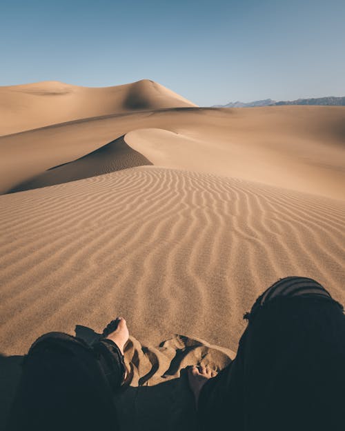 Barefooted Person Sitting on a Desert
