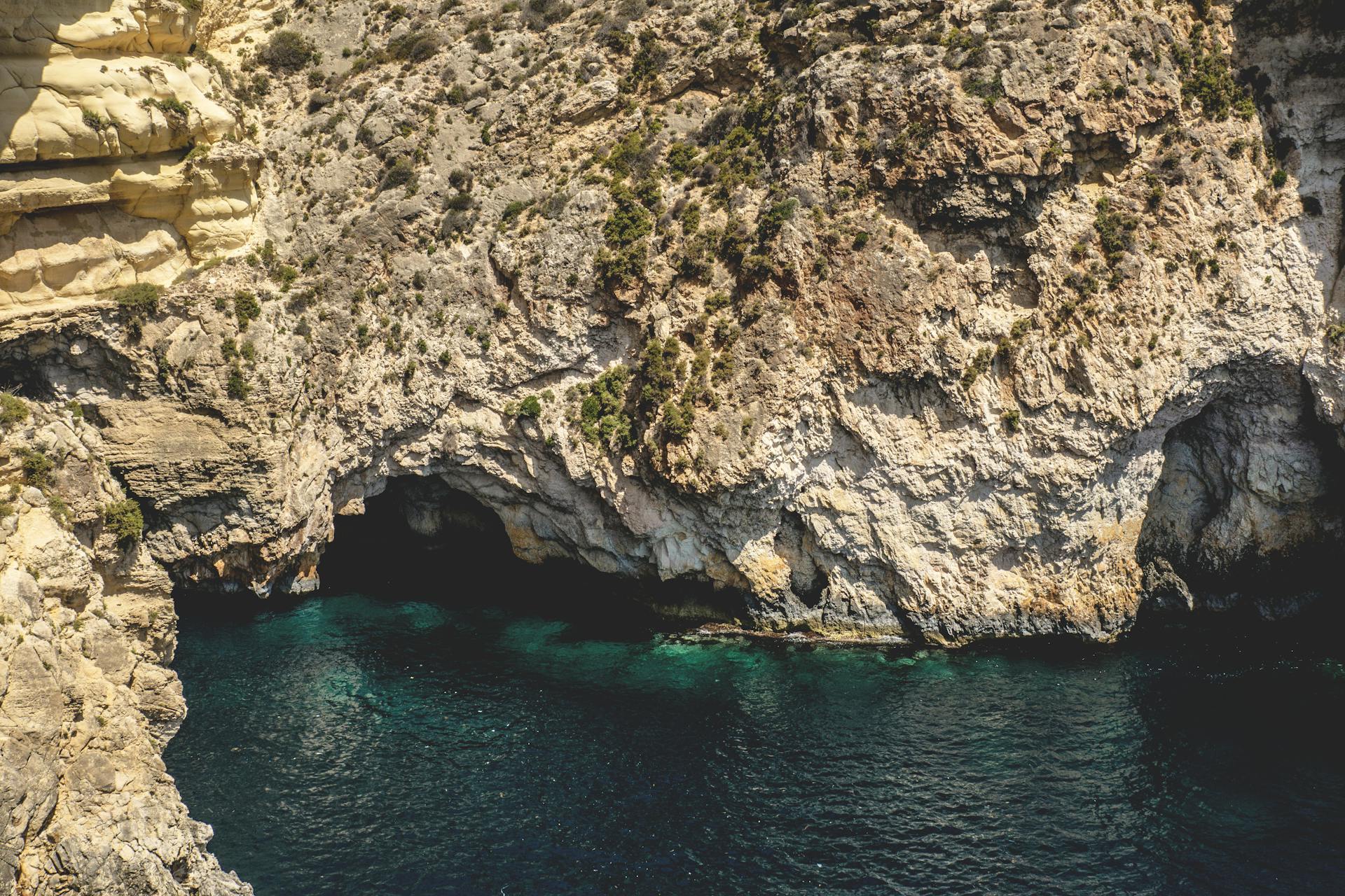 Explore the breathtaking rocky coastline and azure waters of Mgarr, Malta, with this scenic cave view.