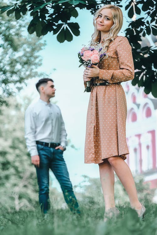 Free Charming woman with bouquet standing in park near boyfriend Stock Photo