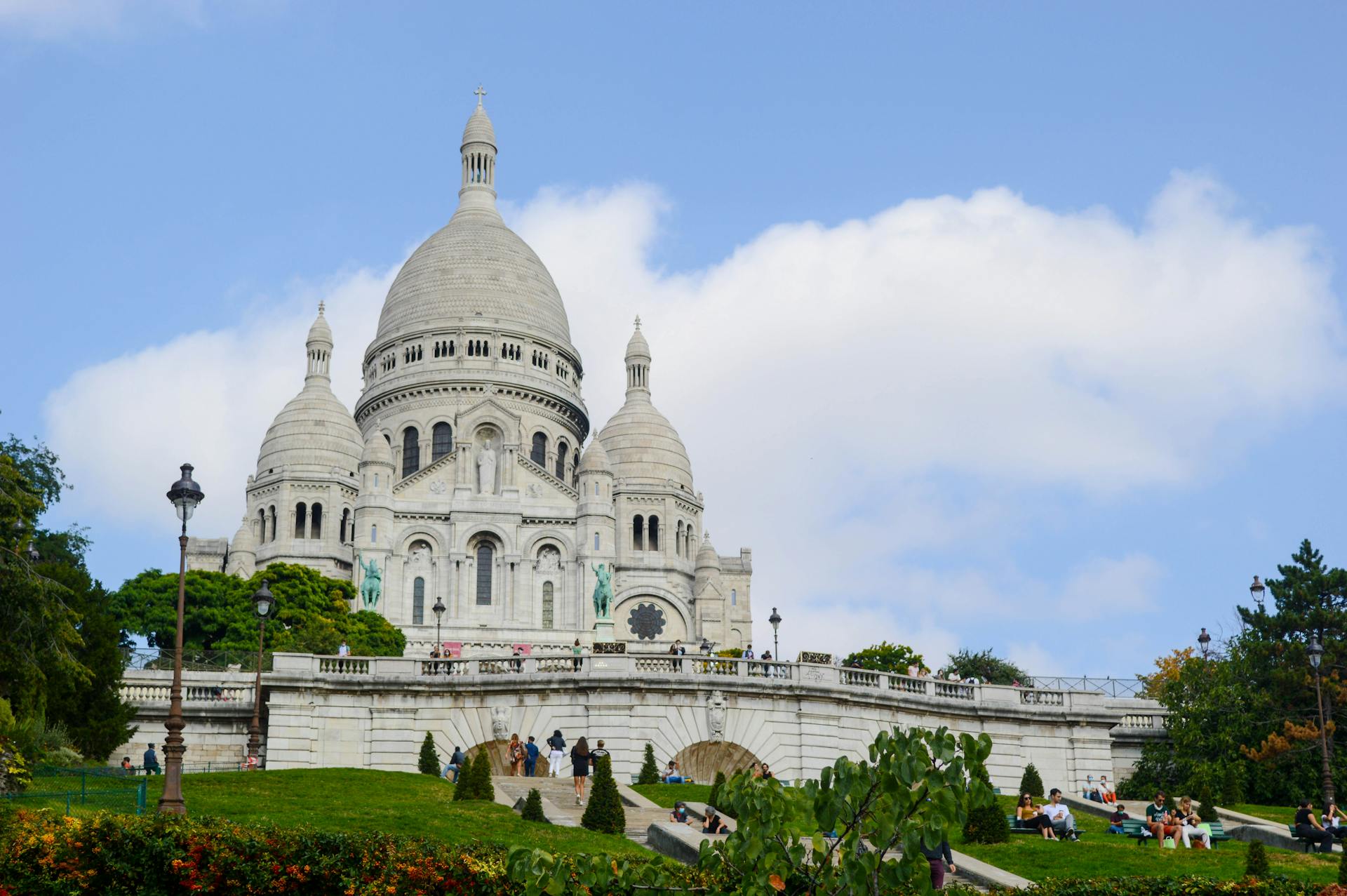 The beautiful Sacre Coeur Basilica under a vibrant blue sky in Paris, surrounded by greenery.