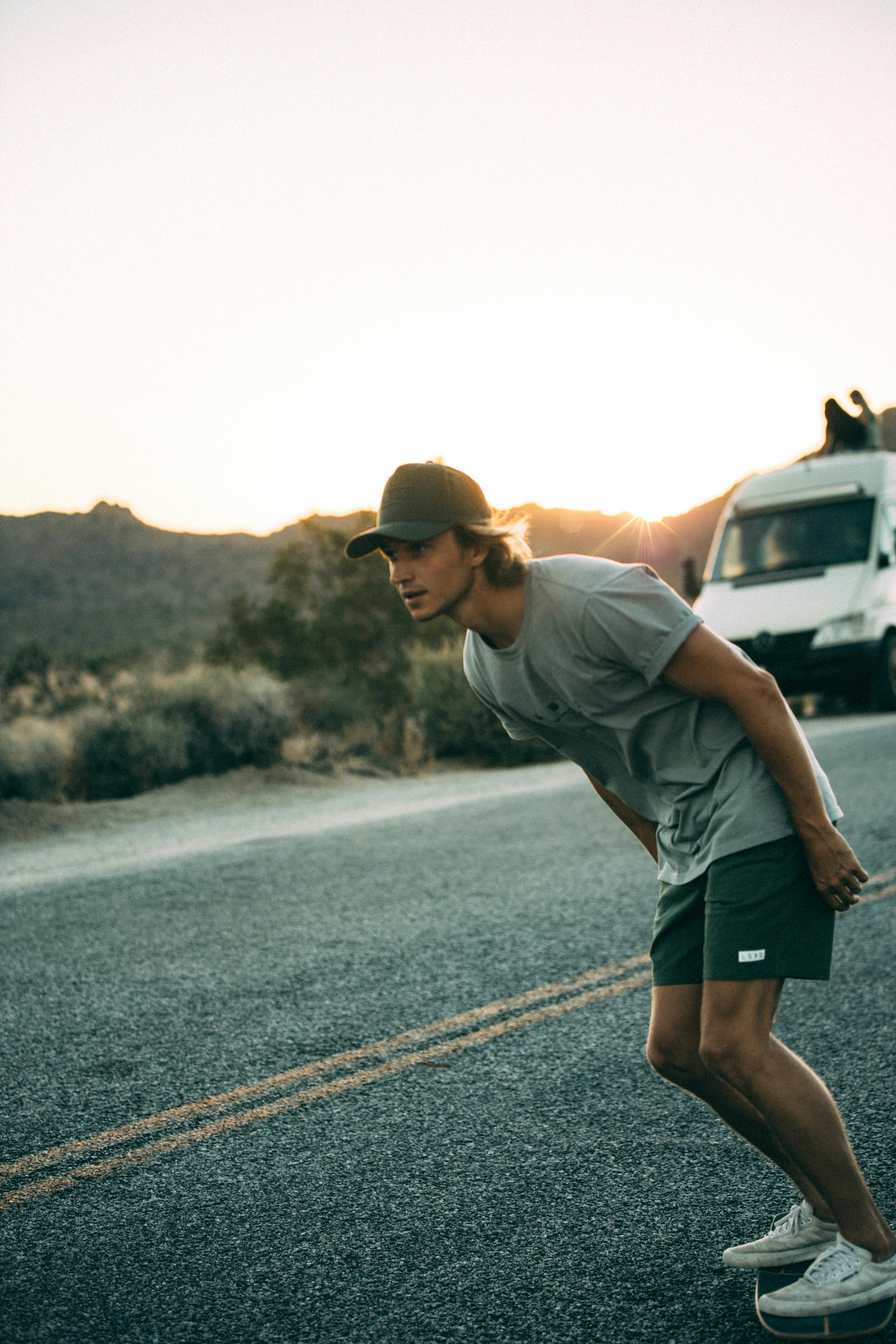 A young man skateboards down a desert road with a sunset backdrop, portraying adventure and freedom.