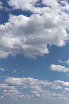 Peaceful sky with fluffy white clouds on a bright sunny day.