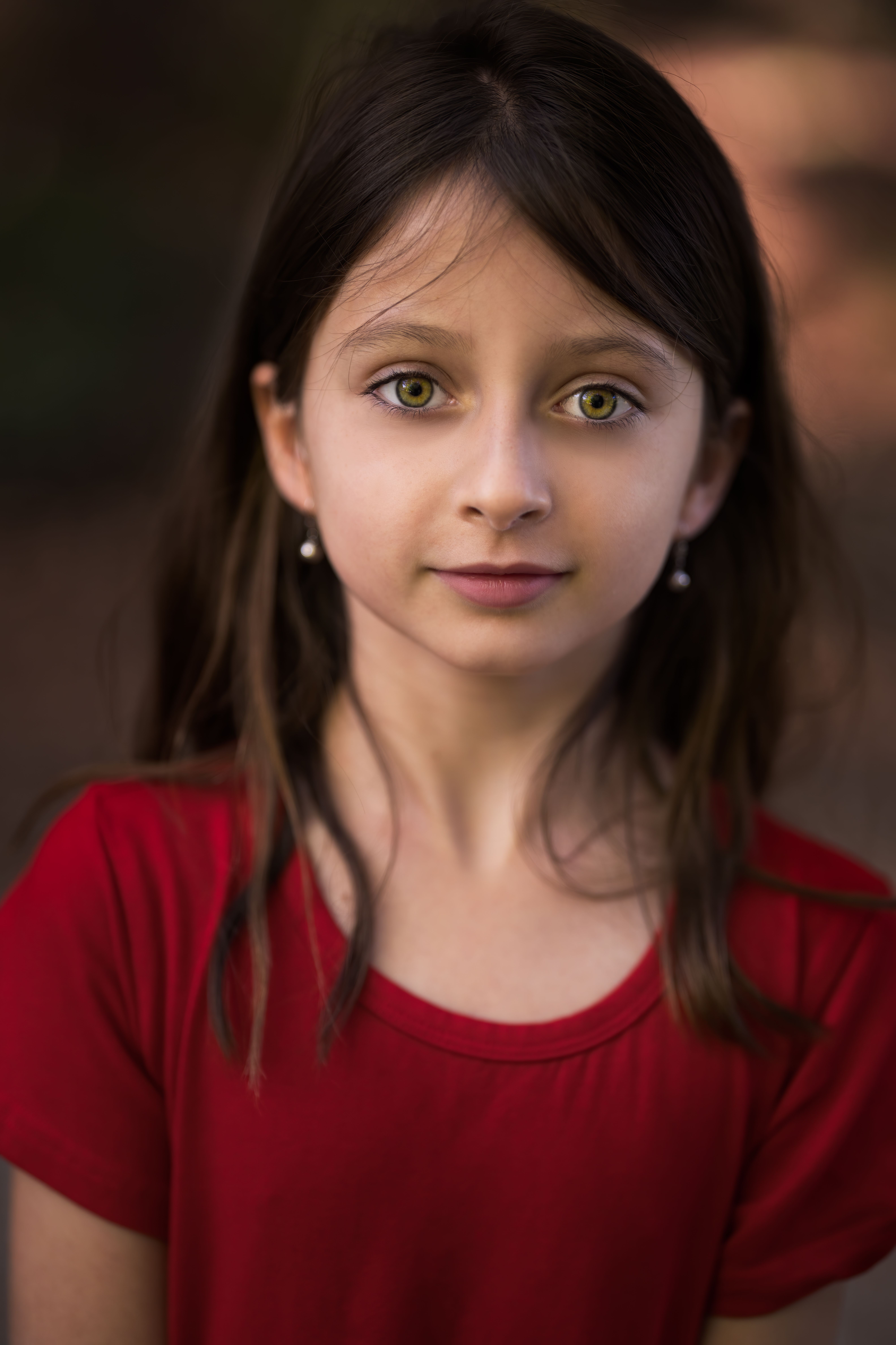 Charming girl in casual apparel with dark hair and earrings looking at camera with sincere gaze