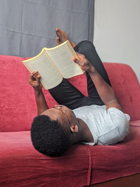 Casual portrait of a man reading a book while lying on a sofa, indoor setting, relaxed atmosphere. Casual portrait of a man reading a book while lying on a sofa, indoor setting, relaxed atmosphere.