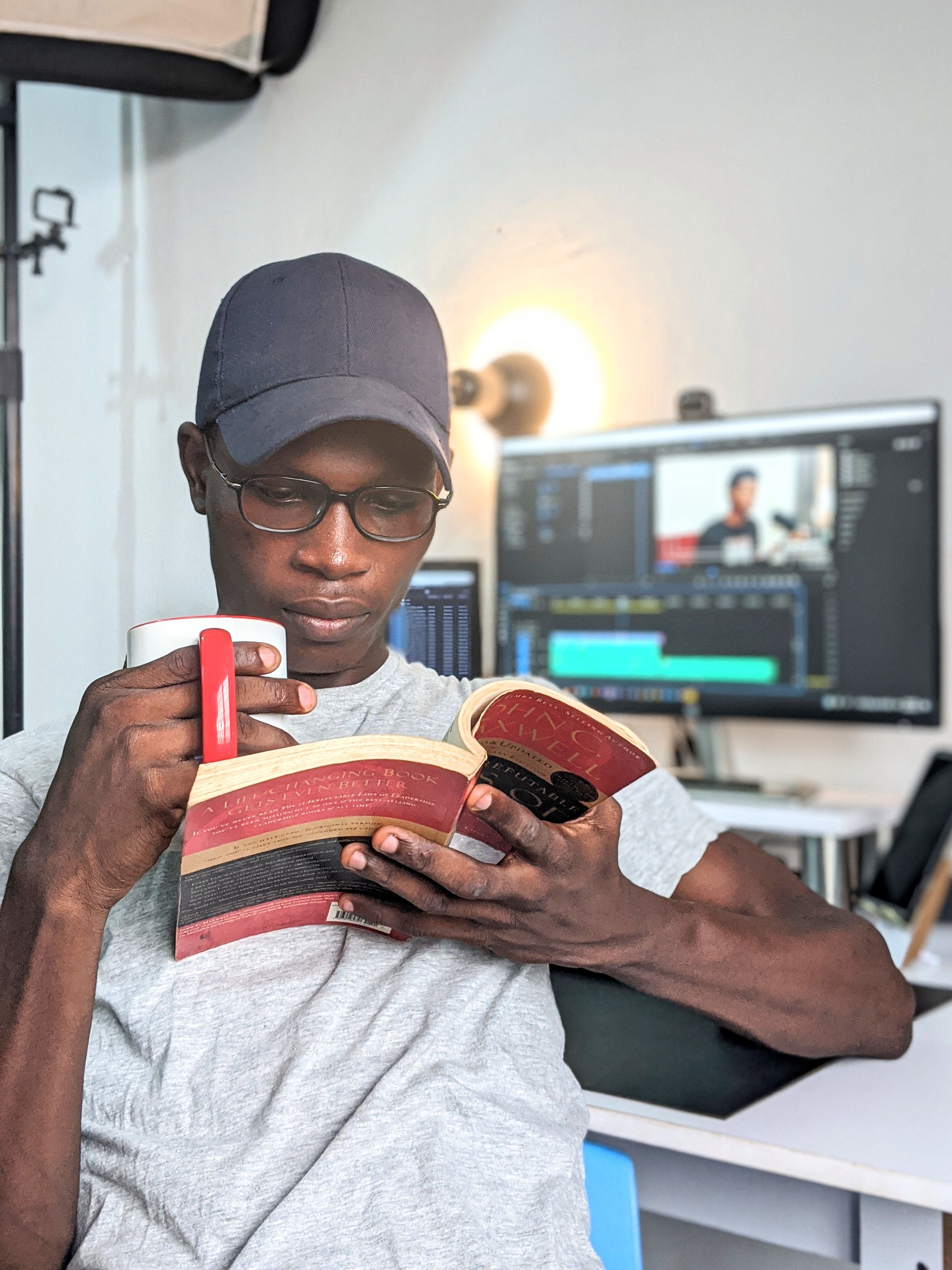 A man enjoys reading a book while holding a mug in a modern home office.
