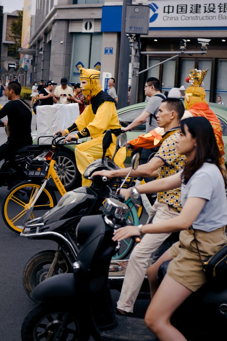 People On Scooters And Bicycles On A City Street In China 