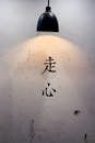 Lamp Light Illuminating Japanese Characters On White Wall