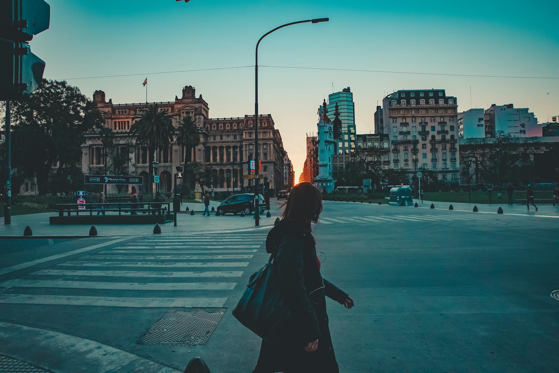 A person crossing a street in San Nicolás, CABA, Argentina during dusk with urban architecture in view.