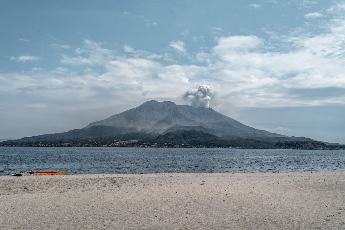 Sakurajima volcano with small ash plume viewed from a sandy beach on Kinko Bay on a clear day