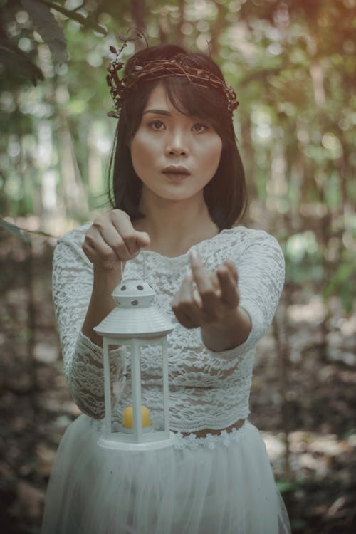 Beautiful Asian woman with lamp in woods