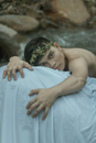 Ethnic man climbing rocky cliff covered with sheet