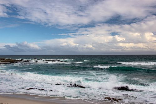 Free Tranquil view of Yzerfontein beach with waves crashing and cloudy skies in South Africa. Stock Photo