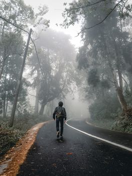 在印度尼西亚巴厘岛，一个人走在一条雾蒙蒙的道路上，周围薄雾弥漫，参天大树环绕