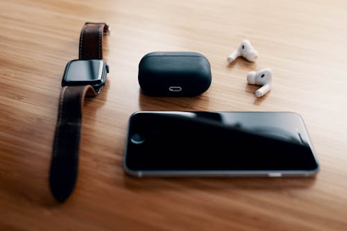 Free Black smart watch and TWS earbuds with charging case and smartphone lying on wooden table Stock Photo