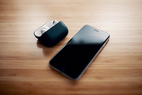 Black smartphone and true wireless earphones on table on table