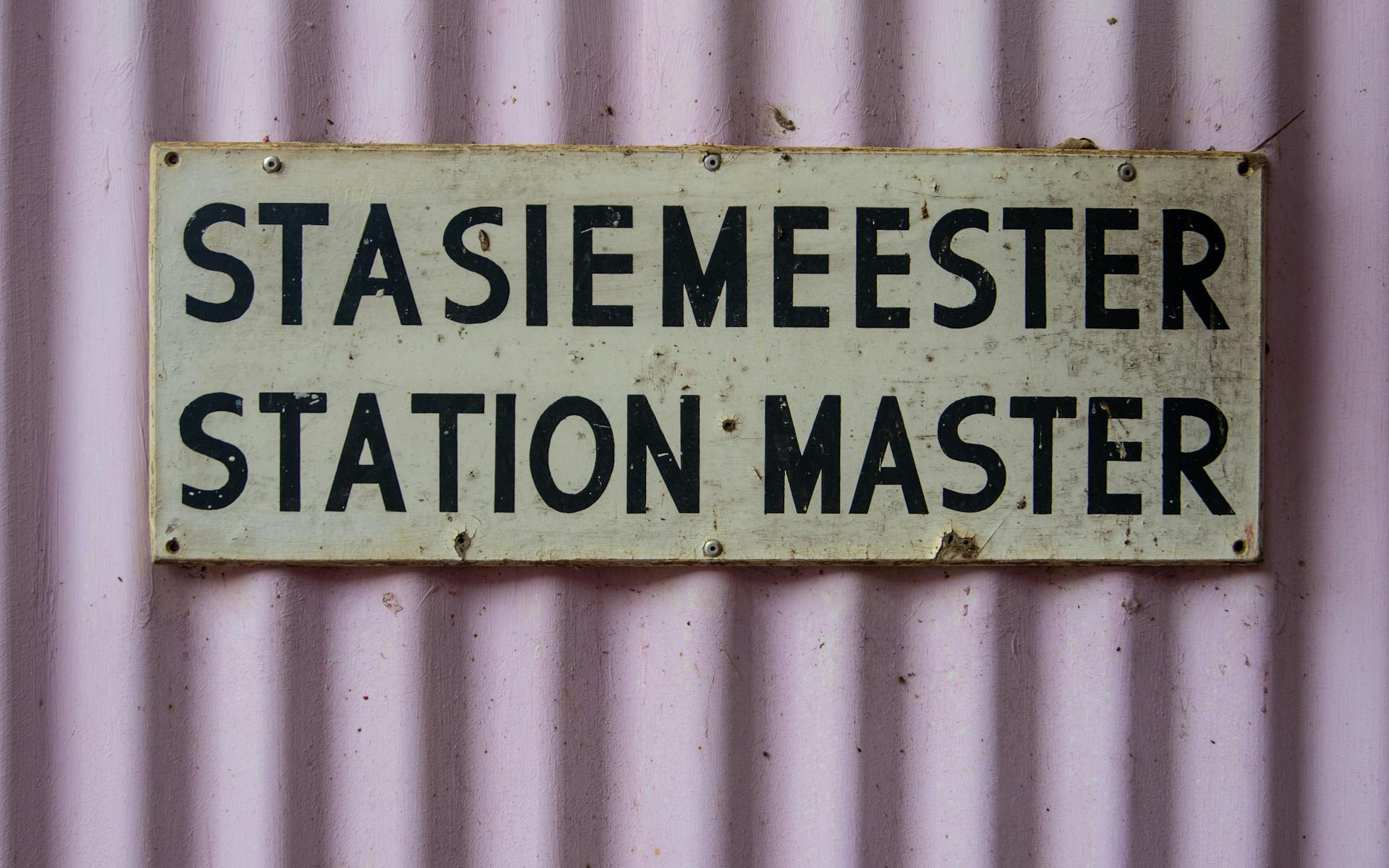 Station Master Plaque Riveted to a Pink Corrugated Wall