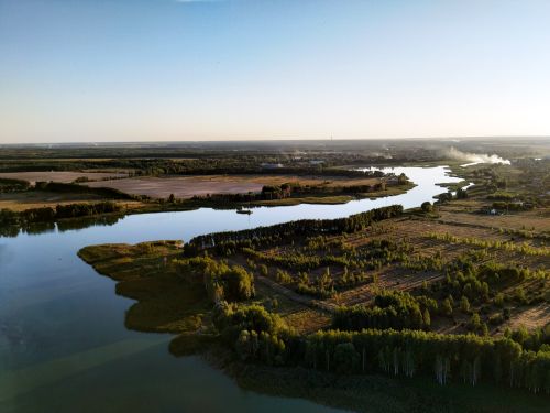 Free Aerial view of a serene river winding through lush countryside under a clear blue sky. Stock Photo