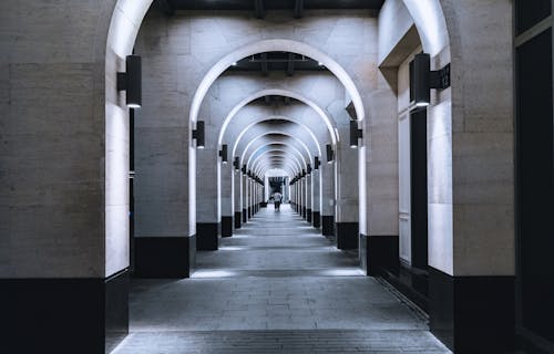 A Person Walking on Arched Hallway