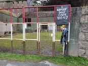 Man in Blue Jacket Standing Near White Metal Fence