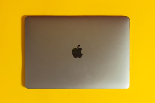 Free A modern laptop with a sleek design on a bright yellow surface, emphasizing minimalism. Stock Photo