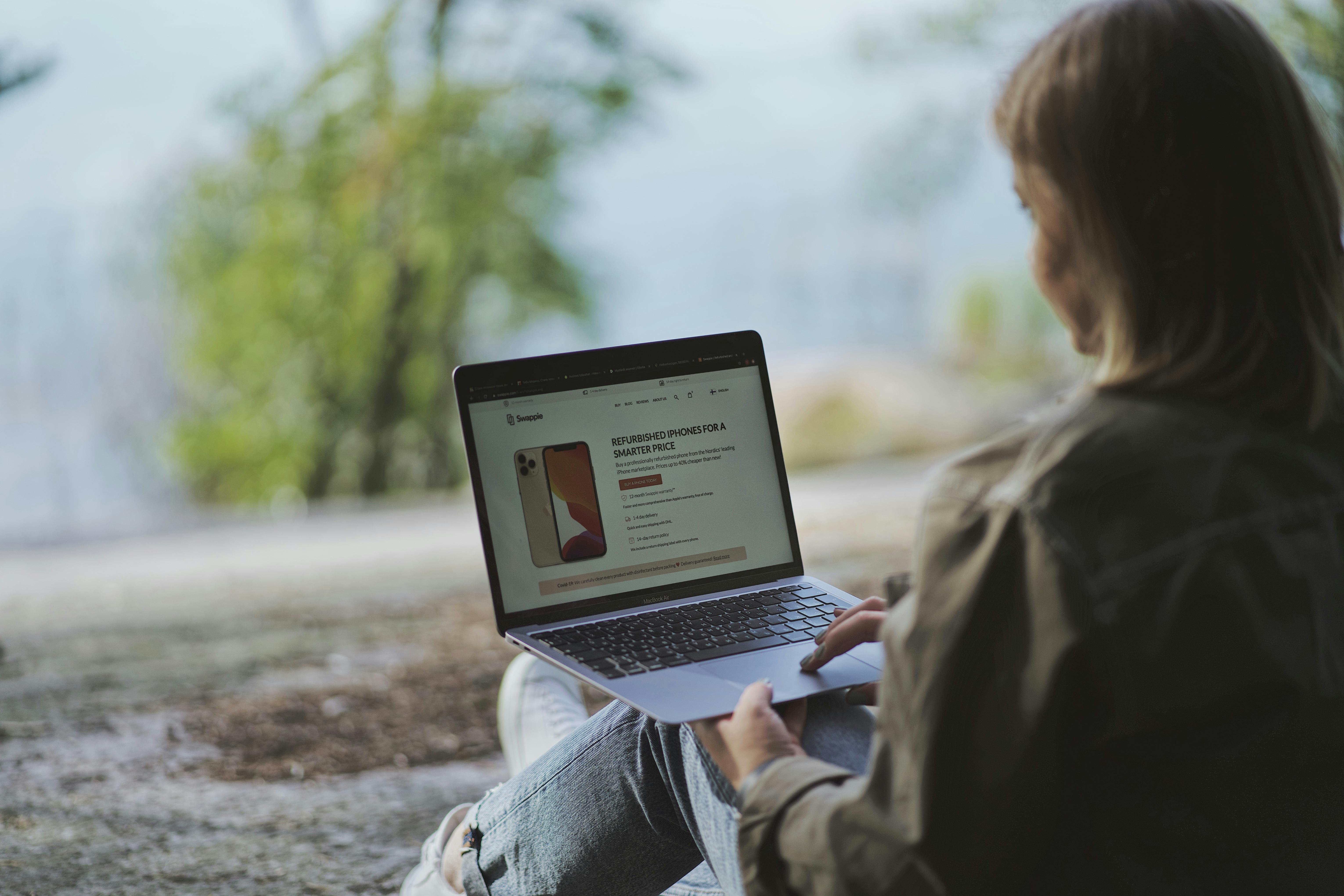 Woman using a laptop outdoors in Helsinki, Finland, showcasing a remote work lifestyle.