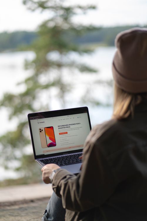 Free Young woman using laptop outside in Helsinki, showcasing a digital nomad lifestyle. Stock Photo