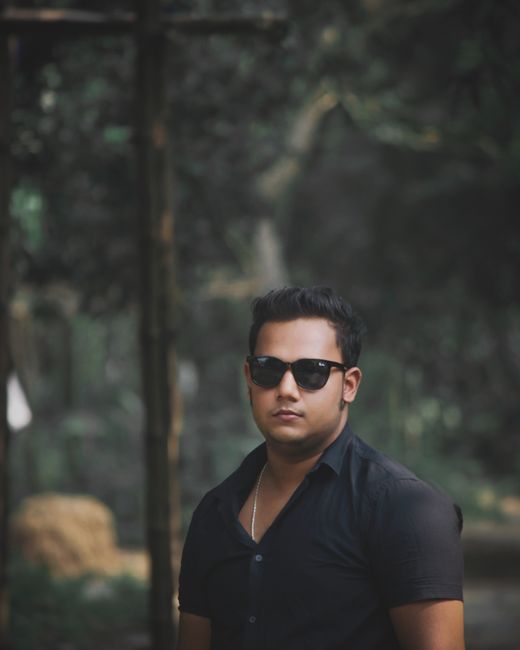 A stylish man in sunglasses poses outdoors in Jamalpur, Bangladesh.