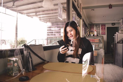 Teenage Girl Using Smart Phone in Restaurant 
