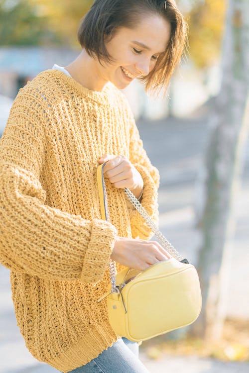 Kostnadsfri bild av gul tröja, håller, handväska