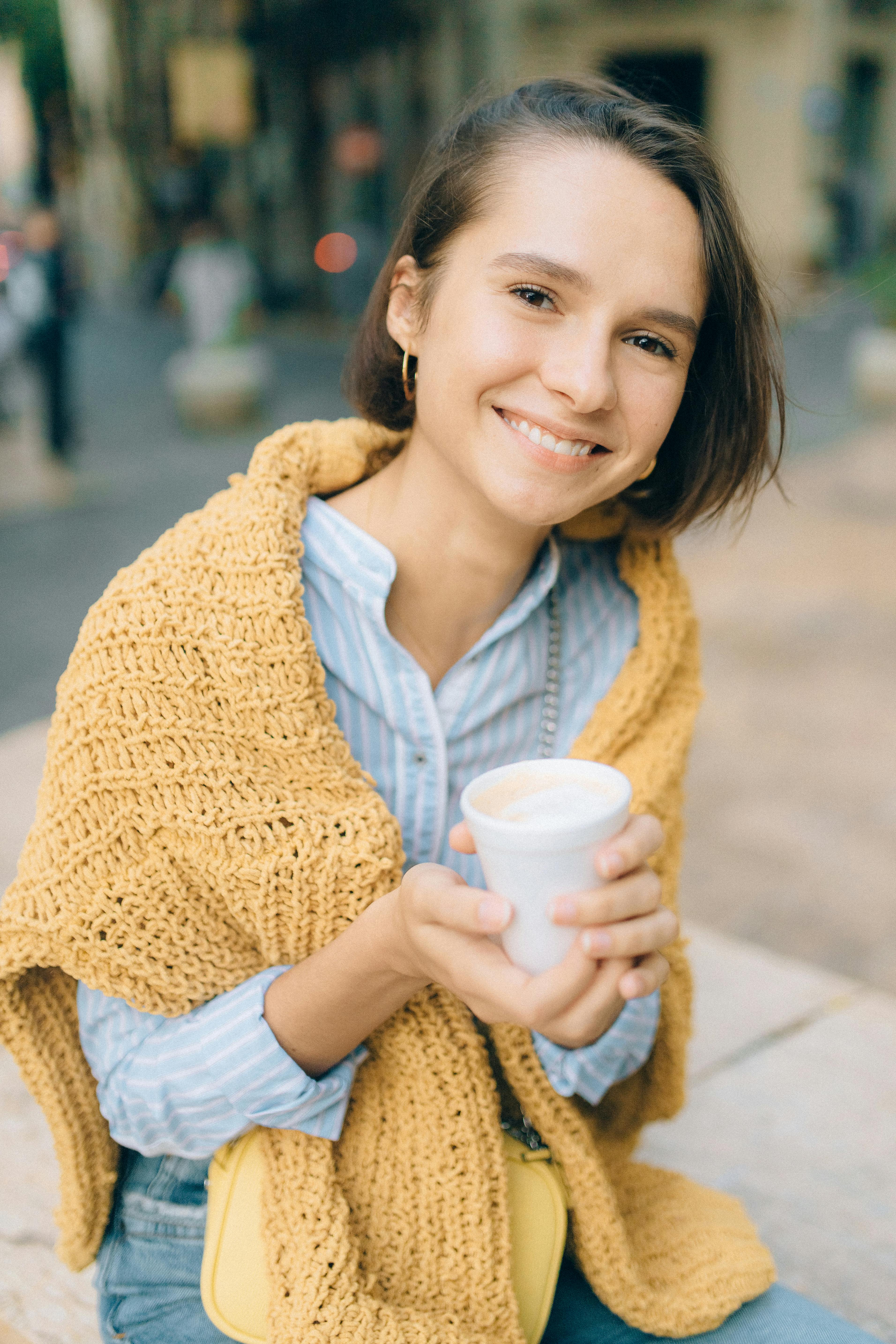 a happy young woman holding a styrofoam cup