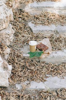 干树叶包围着石头台阶上的布朗尼和咖啡杯，唤起秋天的感觉