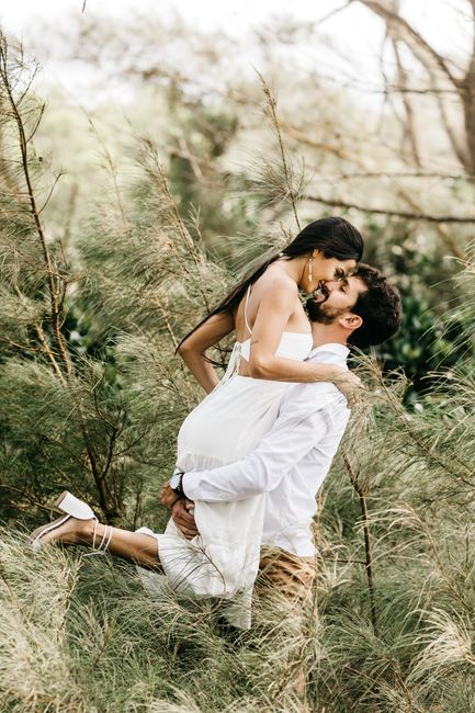 Side view of bright cheerful couple wearing pastel clothes cuddling and kissing in forest